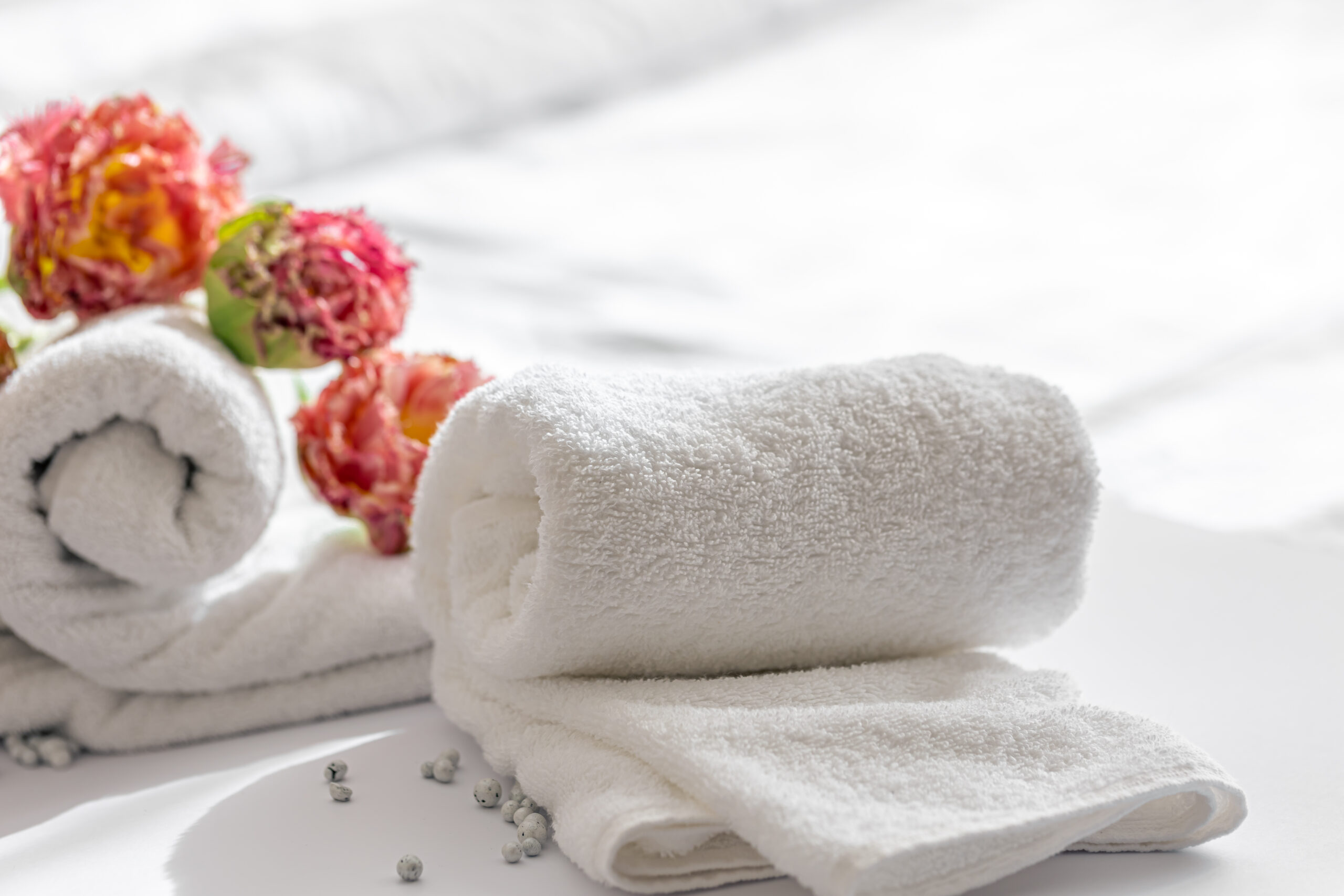 White towel neatly folded with a few orange flowers beside it, showcasing premium quality and luxury by Elysian Thread.