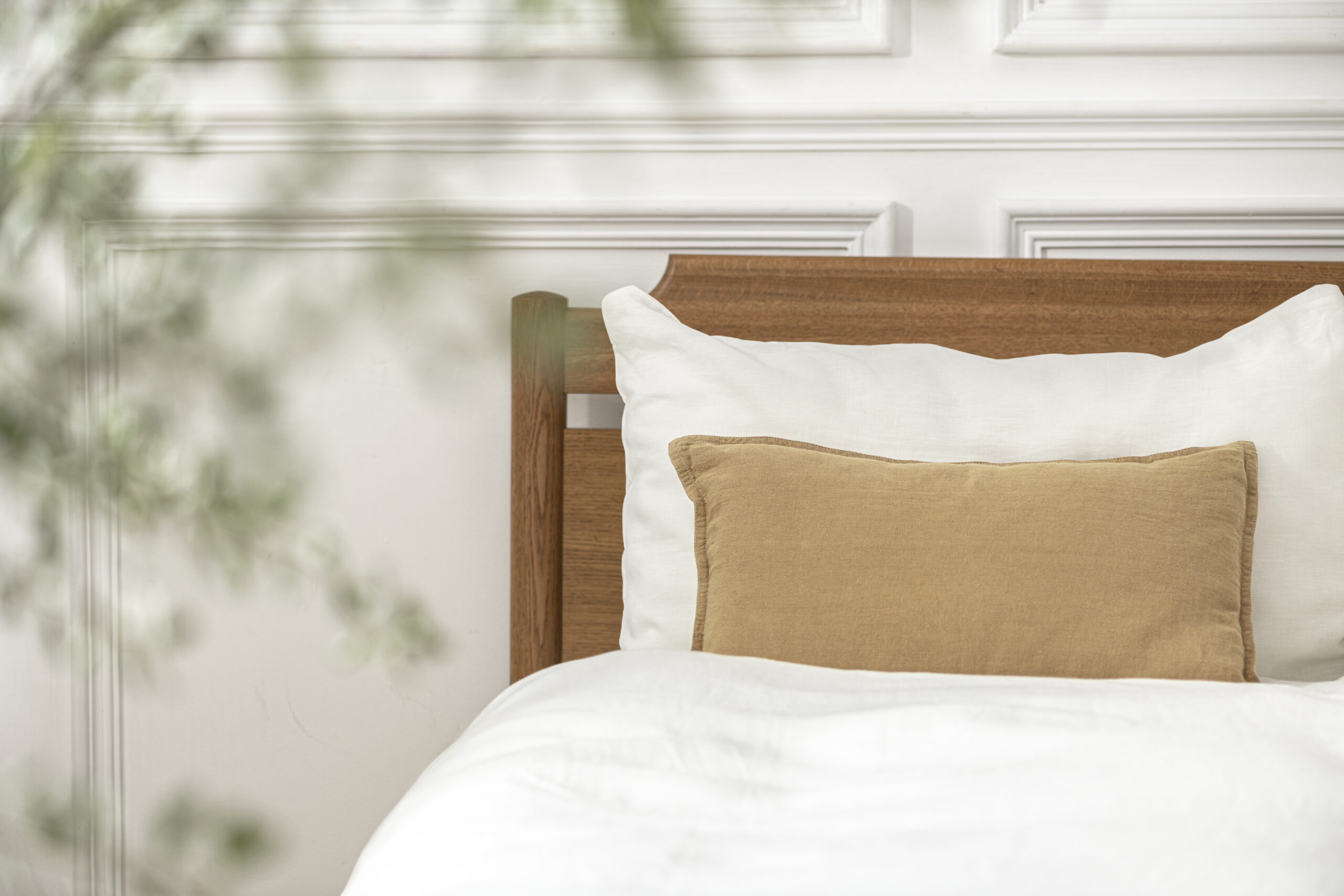 White bedsheet with beige pillows arranged neatly on the bed.